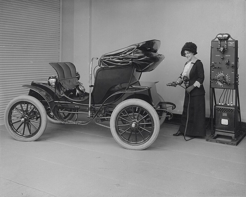 Leasing social: Femme branchant une recharge à une voiture électrique (1912)